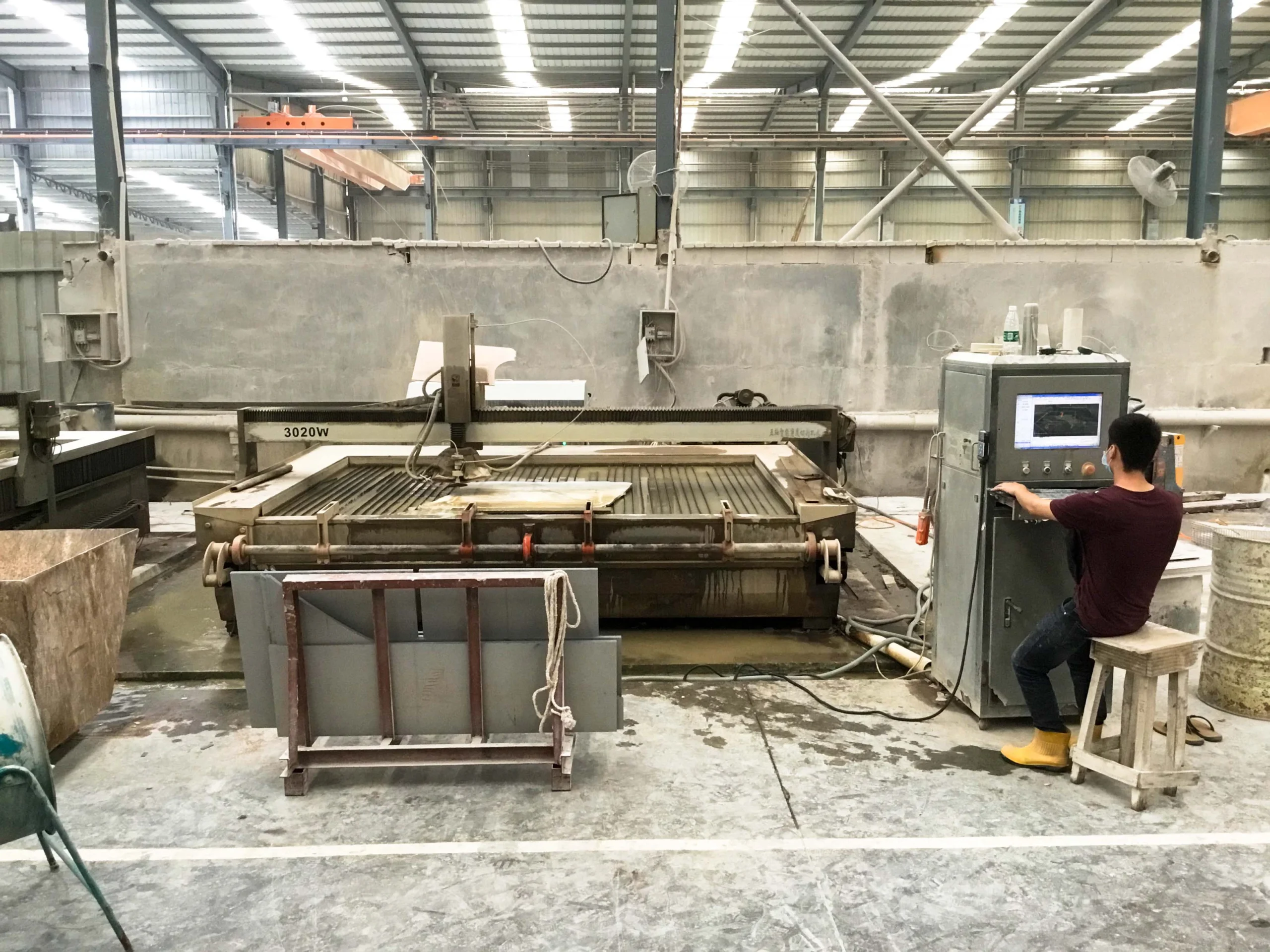 Technician operating CNC waterjet cutting machine for precision stone processing