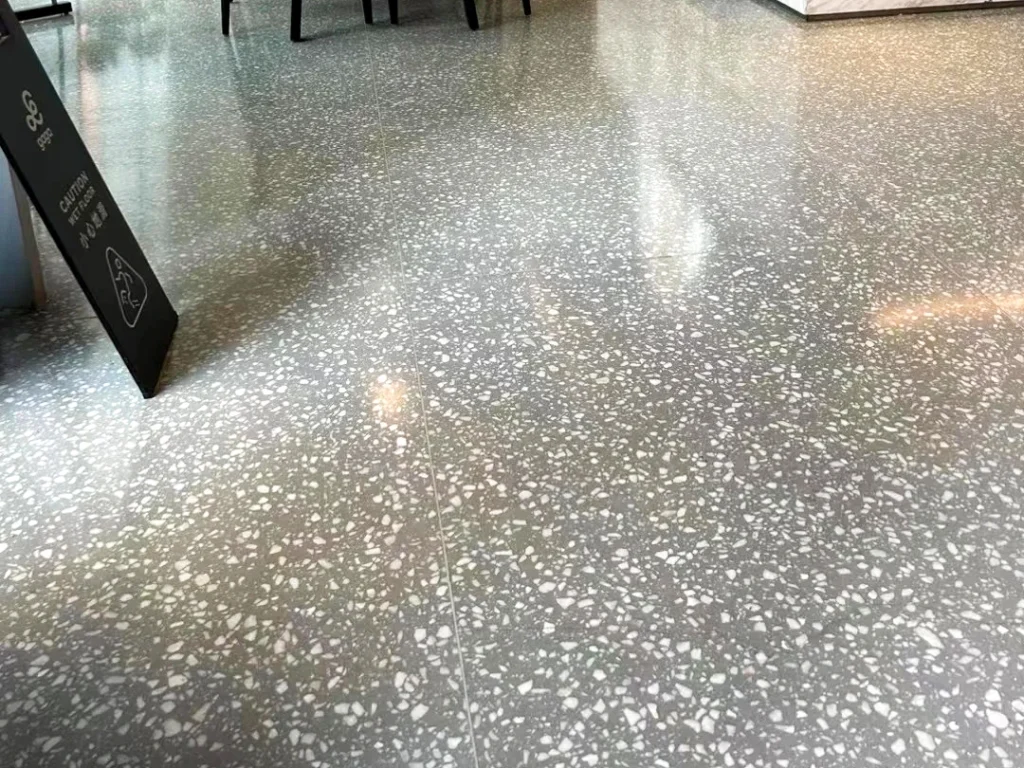 Polished traditional terrazzo floor with grey base and white aggregate, durable flooring for retail and public areas