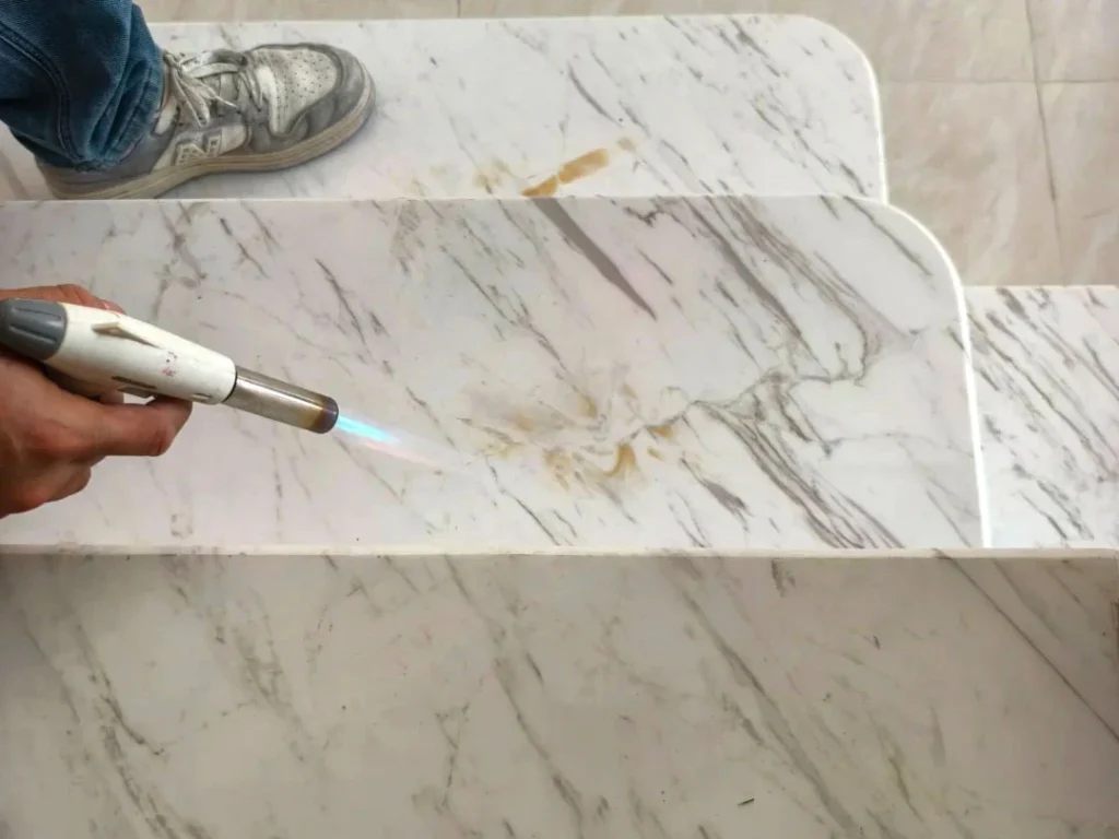 Heating yellow stains on marble with a torch as the first step to remove yellow stains on marble
