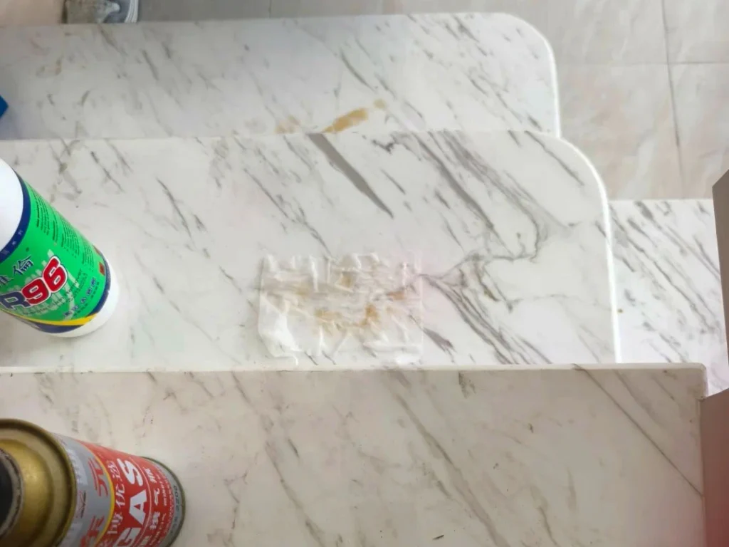 Applying marble stain remover with paper towel to remove yellow stains on marble steps